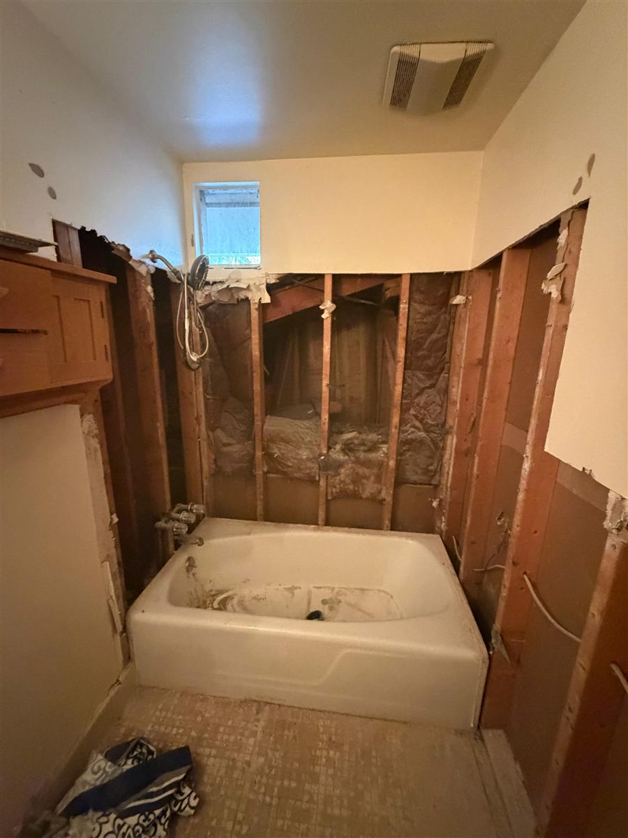 Bathroom walls stripped to studs before drywall repair